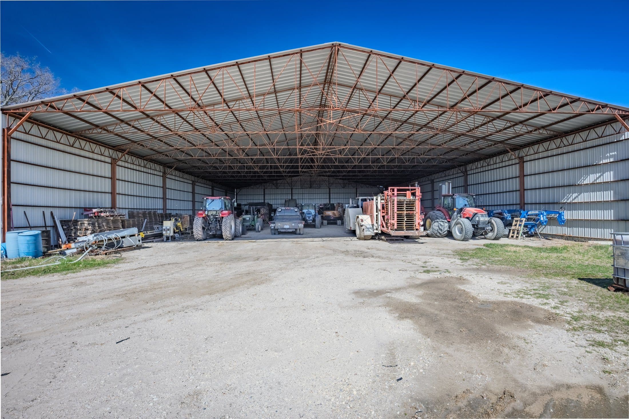 Open-bay shop interior with the multi-brand tractor fleet lined up — Case, John Deere, New Holland, and Ford units