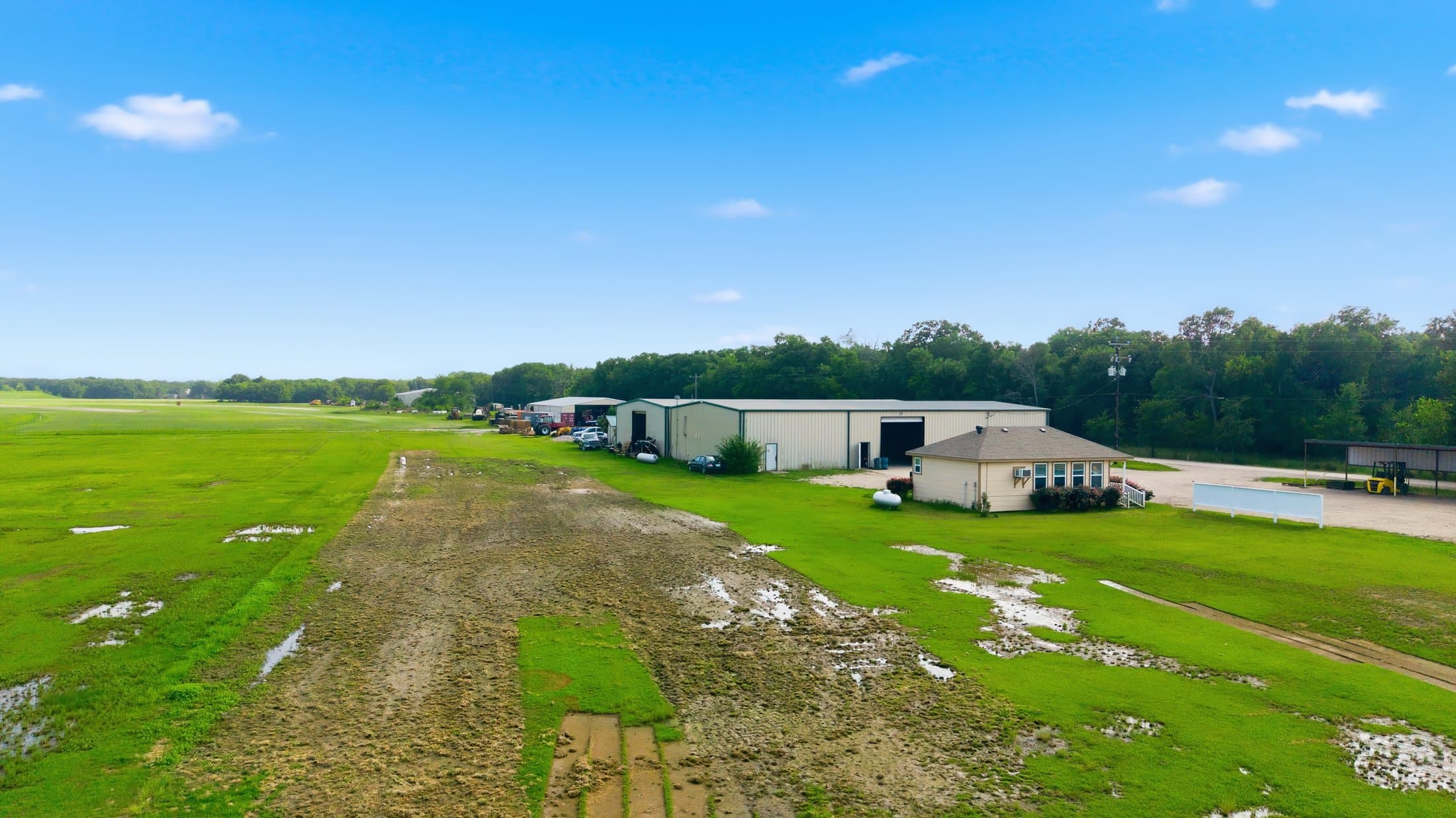 Wide summer aerial across the primary site with tree-lined boundaries