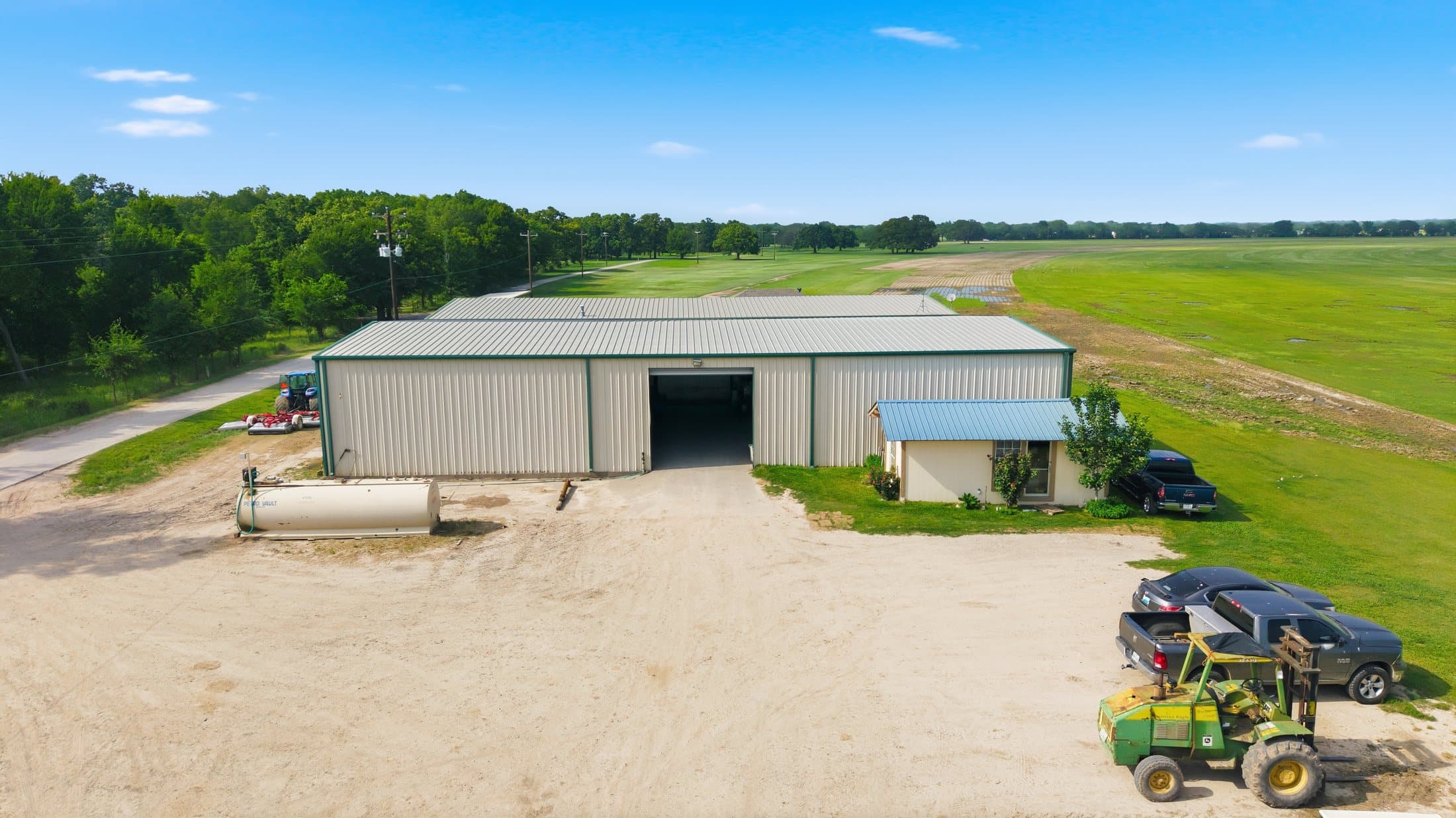 Summer aerial of a workshop building with adjacent equipment and green production fields