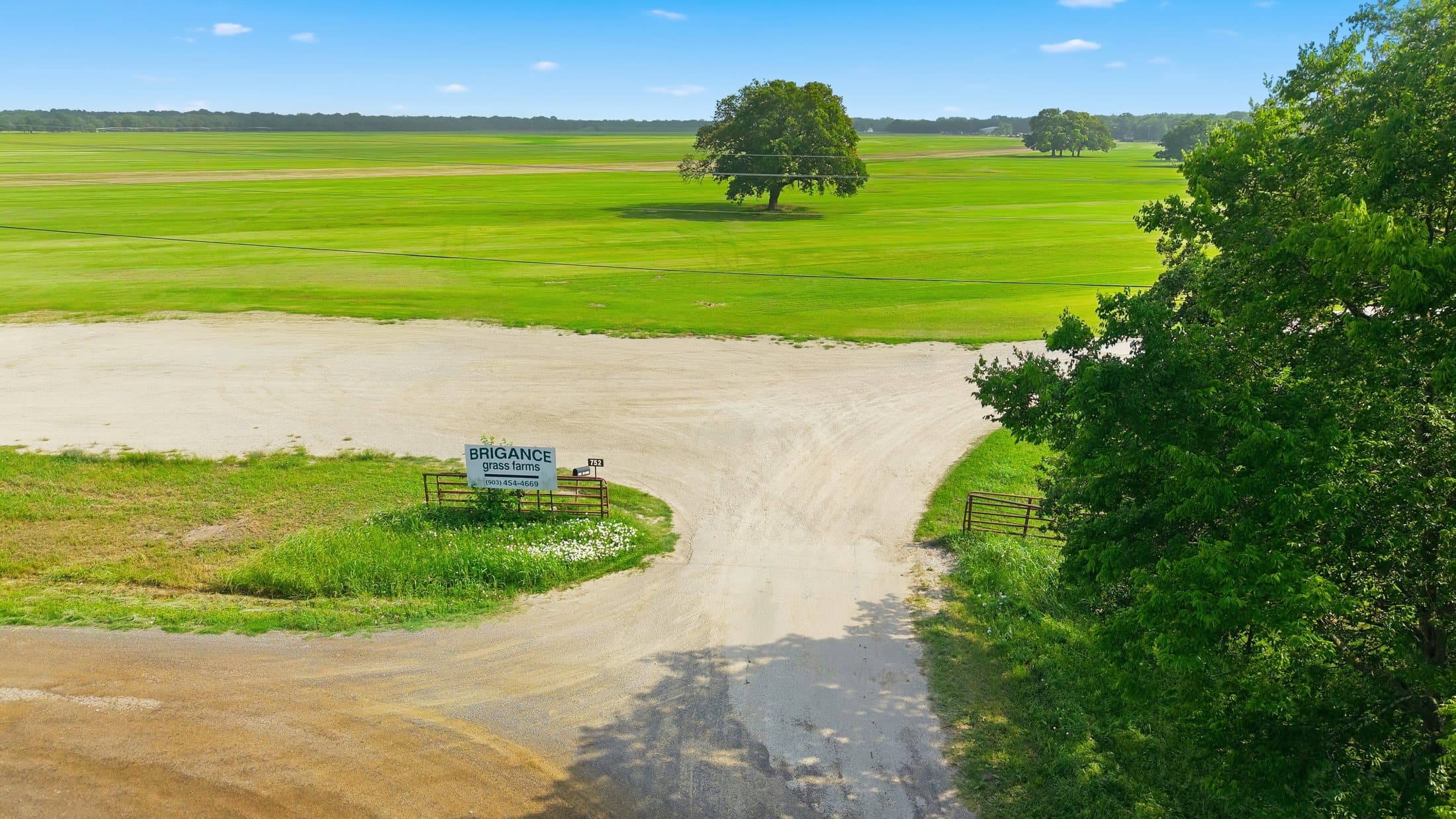 Summer aerial of the property entry sign with cultivated fields in the background