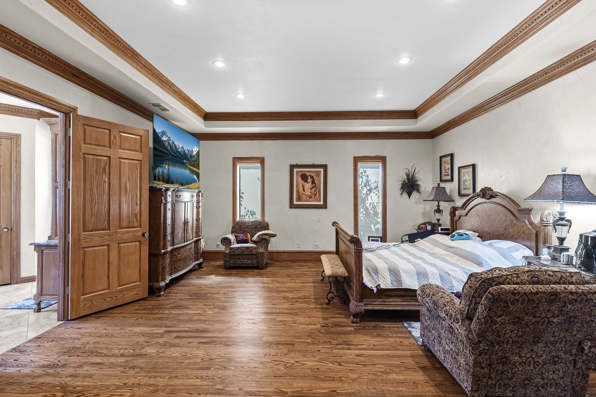 Main residence master bedroom with hardwood floors and tray ceiling